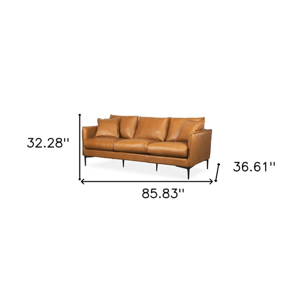 HomeRoots 86" Tan Leather Sofa with Toss Pillows, Sleek Black Metal Legs, Vintage Charm & Modern Comfort 607327