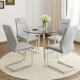 English Elm A Modern Minimalist Round Transparent Tempered Glass Table With Silver Metal Legs and 4 Modern Pu Leather High-Backed Dining Chairs For A Luxurious Experience.